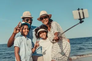 Family taking a selfie at the beach with a selfie stick